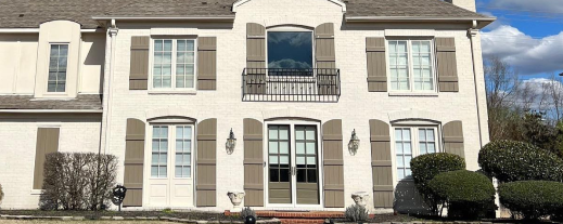 Elegant two-story home with beige stucco exterior and gray shutters
