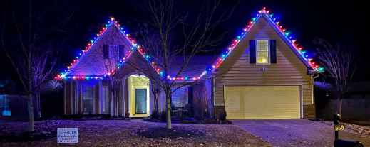 Suburban house decorated with colorful Christmas lights outlining rooflines at night