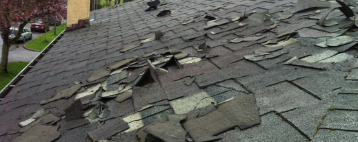 Damaged roof with missing and curled asphalt shingles needing repair