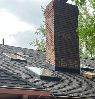 Damaged roof with missing shingles and exposed brick chimney after storm damage