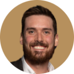 Professional headshot of smiling man with beard and dark hair on beige background
